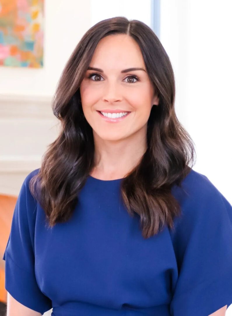 A woman in blue shirt smiling for the camera.