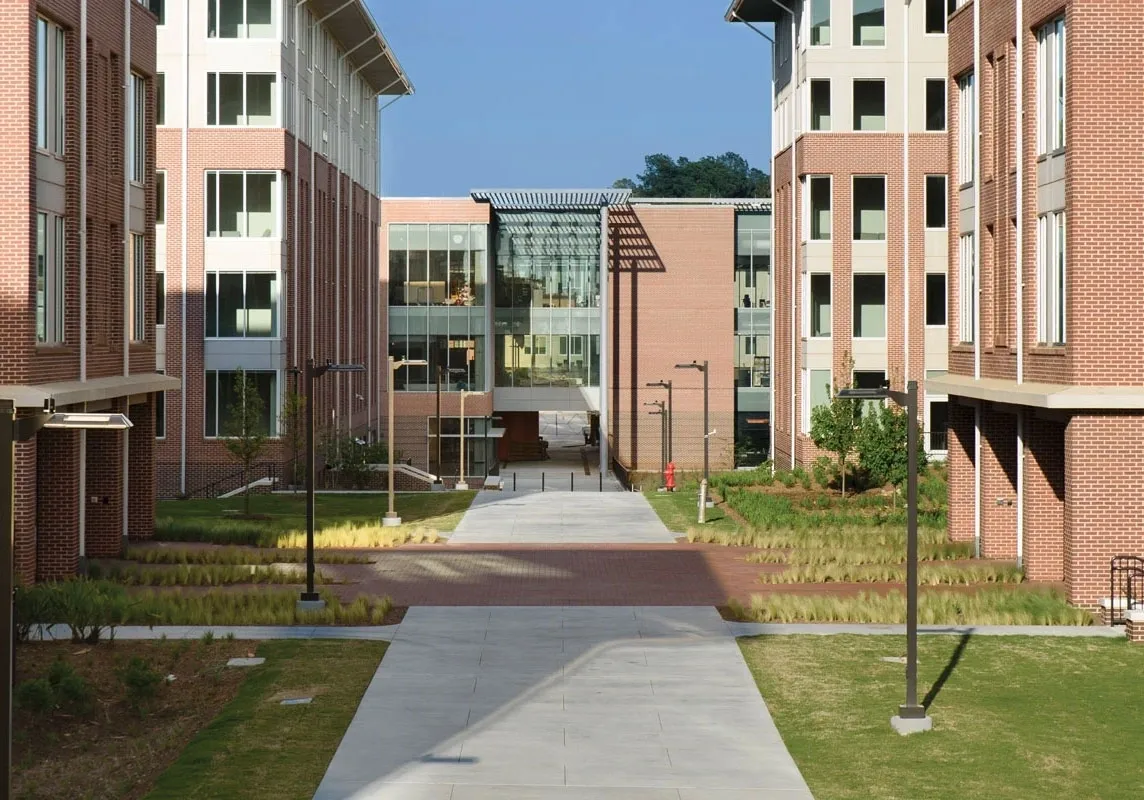 A walkway between two buildings with grass growing on the ground.