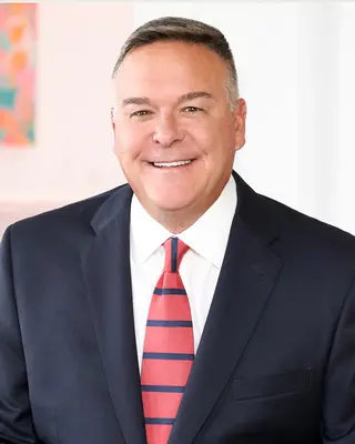 A man in a suit and tie smiling for the camera.